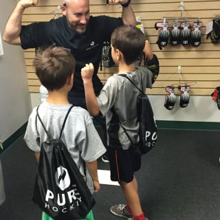 Pure Hockey Associate Flexing Biceps With Two Young Children