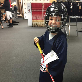 Young Child Wearing Hockey Helmet and Holding Hockey Stick Posing