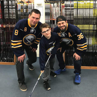 Two Buffalo Sabres Players Posing With One Child at Learn to Play Event
